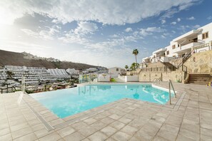 A swimming pool with a view of a hillside residential area.