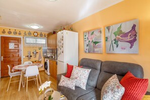 A compact living space with a dining area, kitchenette, and a sofa with floral cushions.
