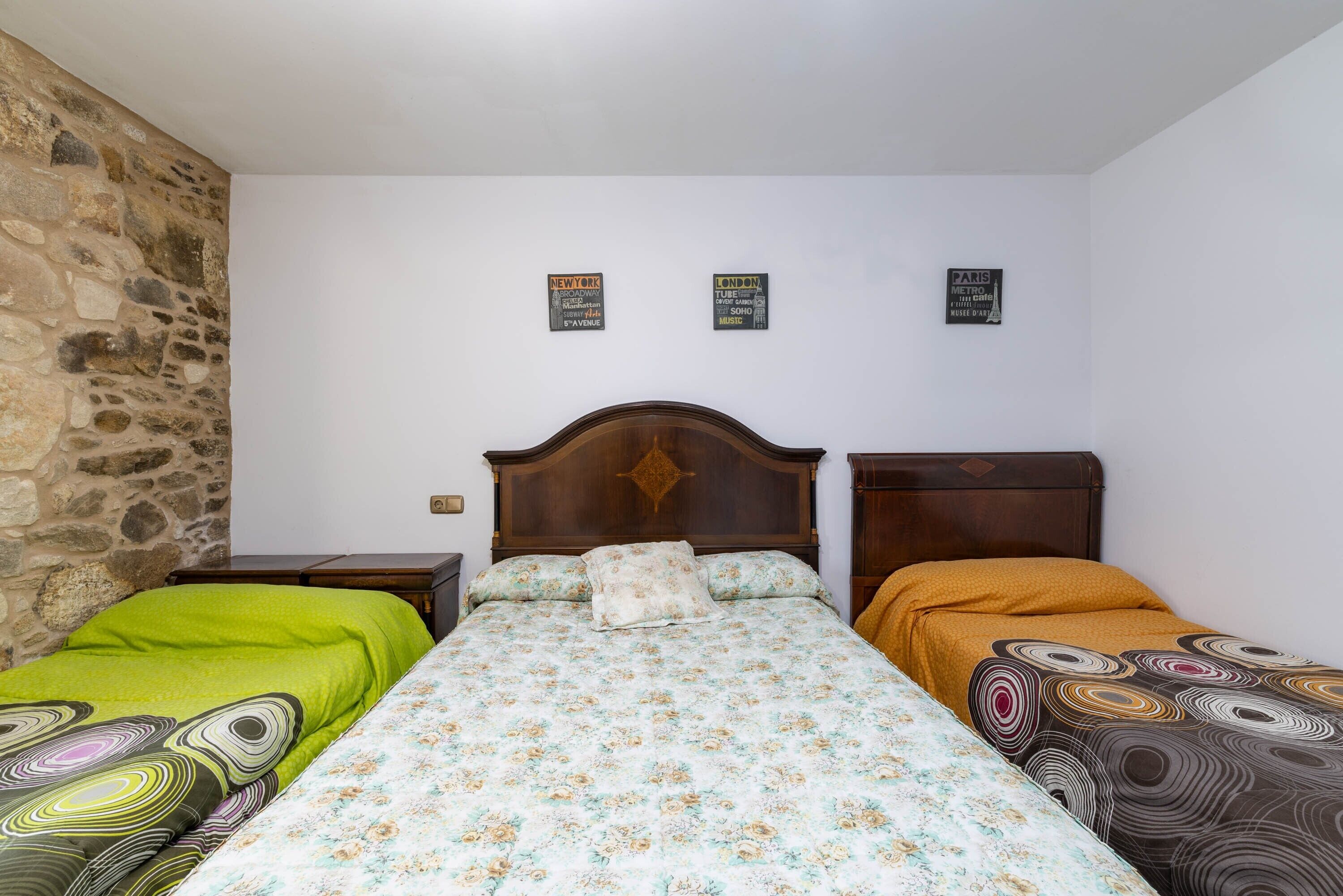 A room with a bed, two nightstands, a stone wall, and three signs on the wall.