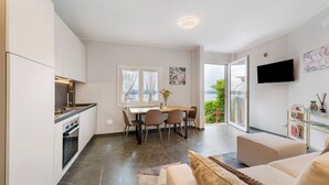 Una cocina moderna con zona de comedor, televisor de pantalla plana y un amplio ventanal.