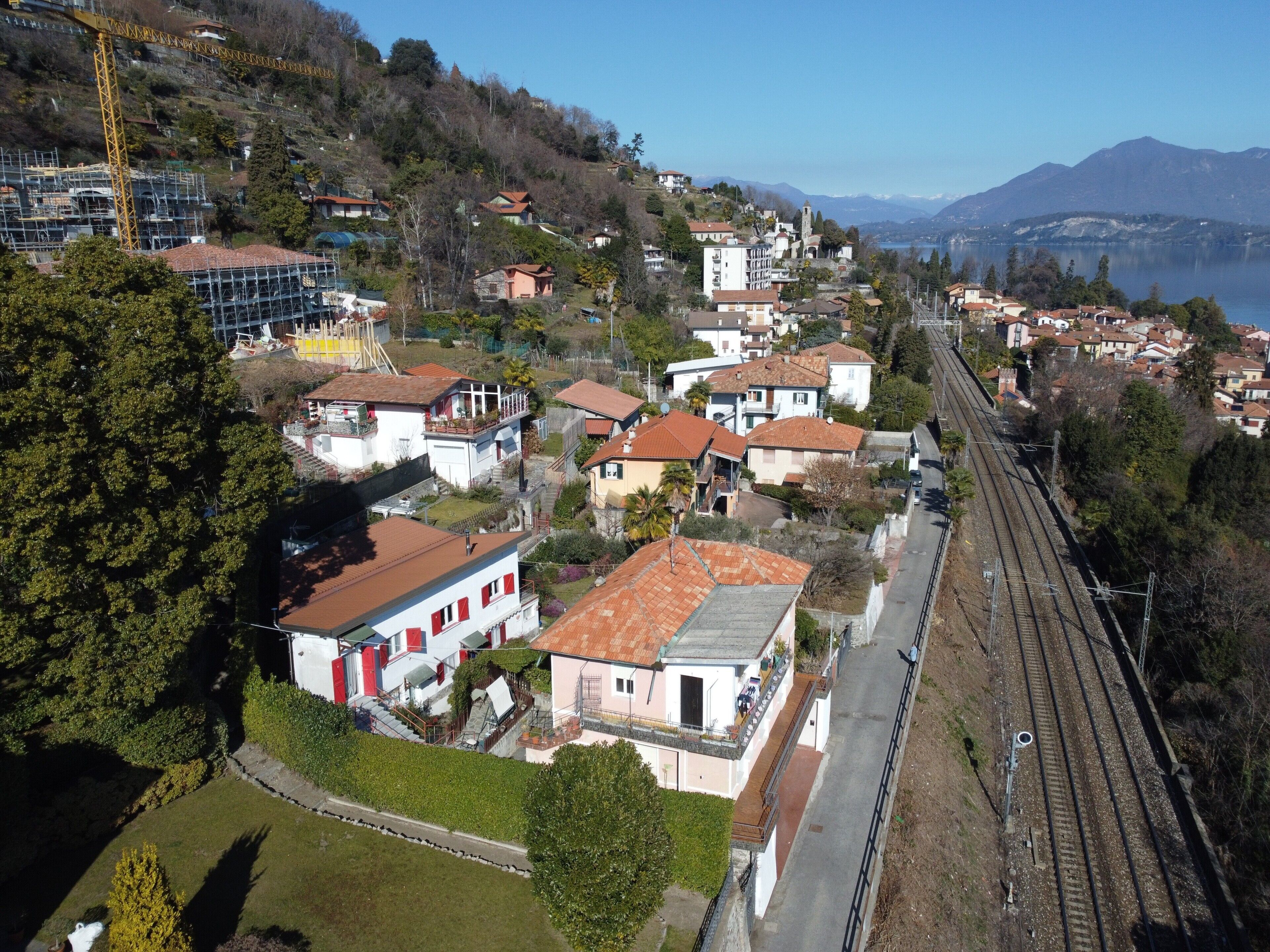 A residential area with houses, a railway track, and a mountainous backdrop.
