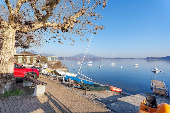 A lakeside dock with boats, a red car, and a tree.