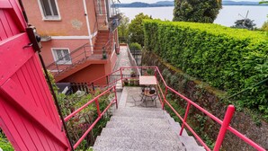 Una escalera lleva a un balcón con vista a un lago y montañas.