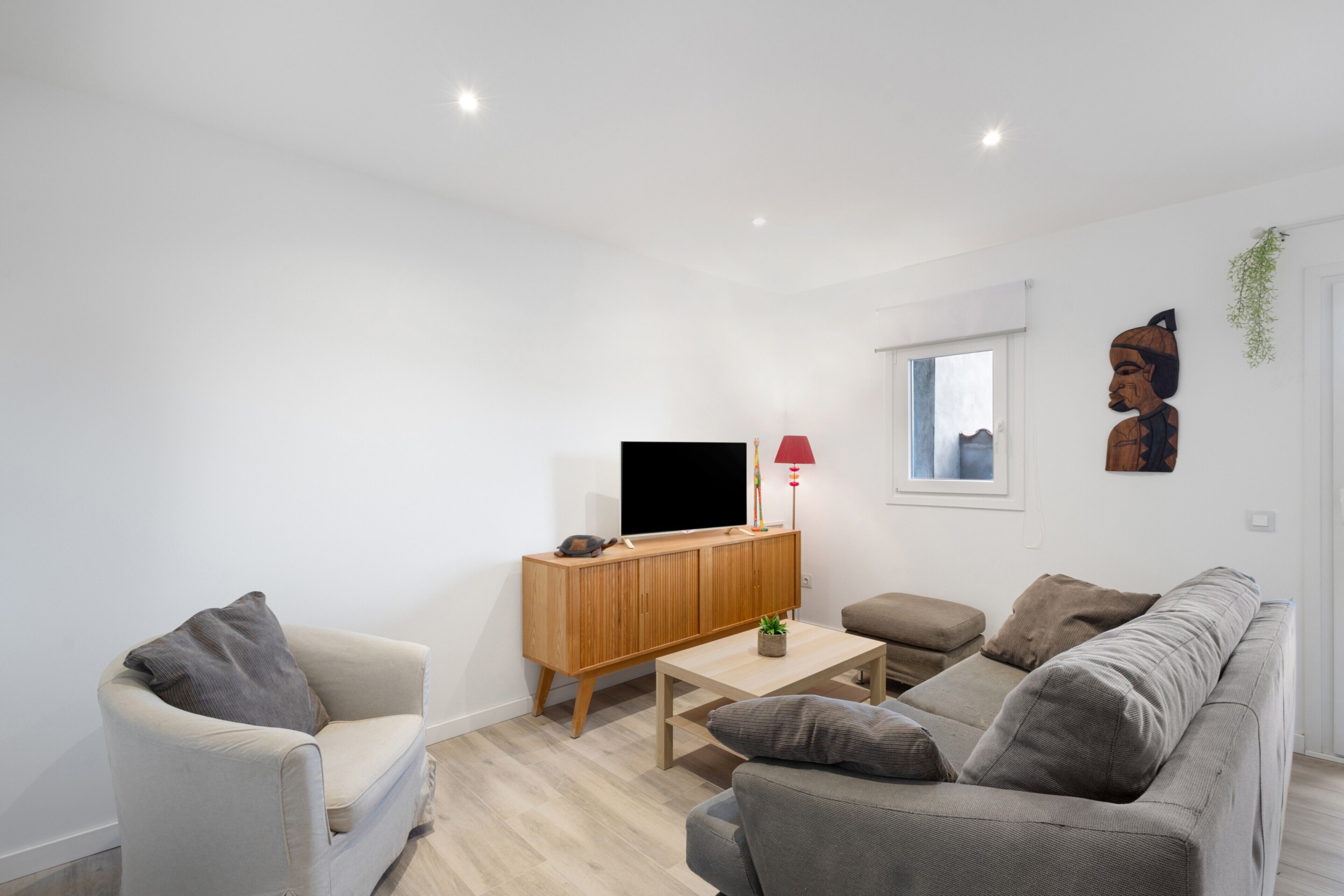 A modern living room with a sofa, a television, a cabinet, and a small table.