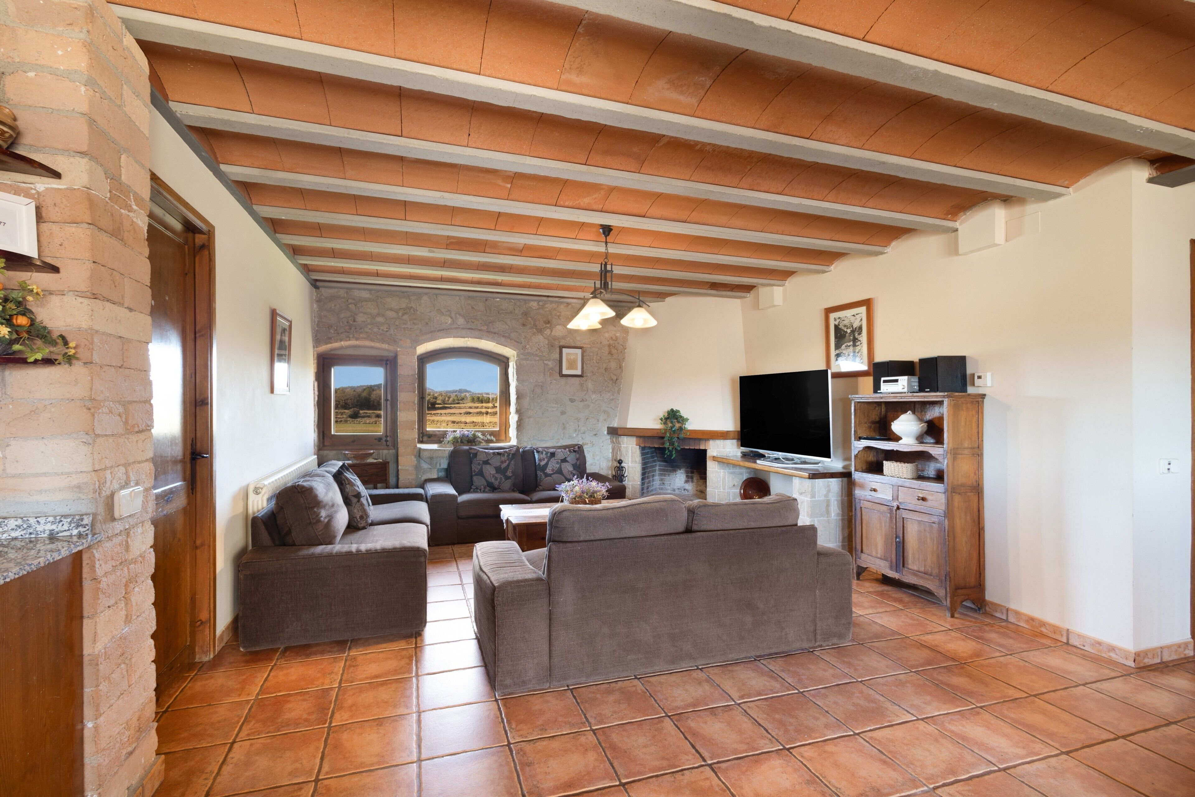 Una sala de estar con sofá, televisor y una zona de cocina con armarios y chimenea.