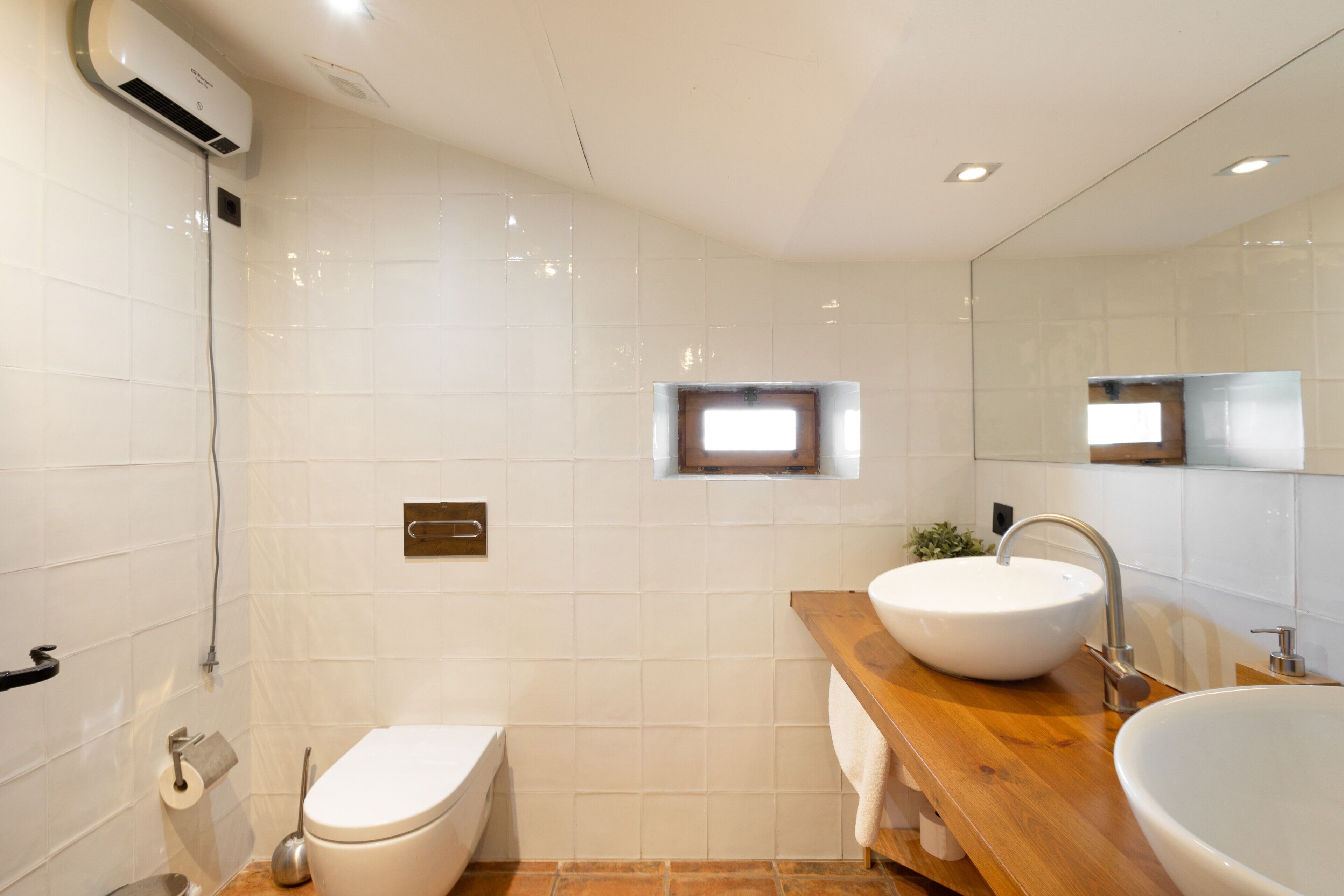 Un baño con inodoro, lavabo, espejo y ventana.