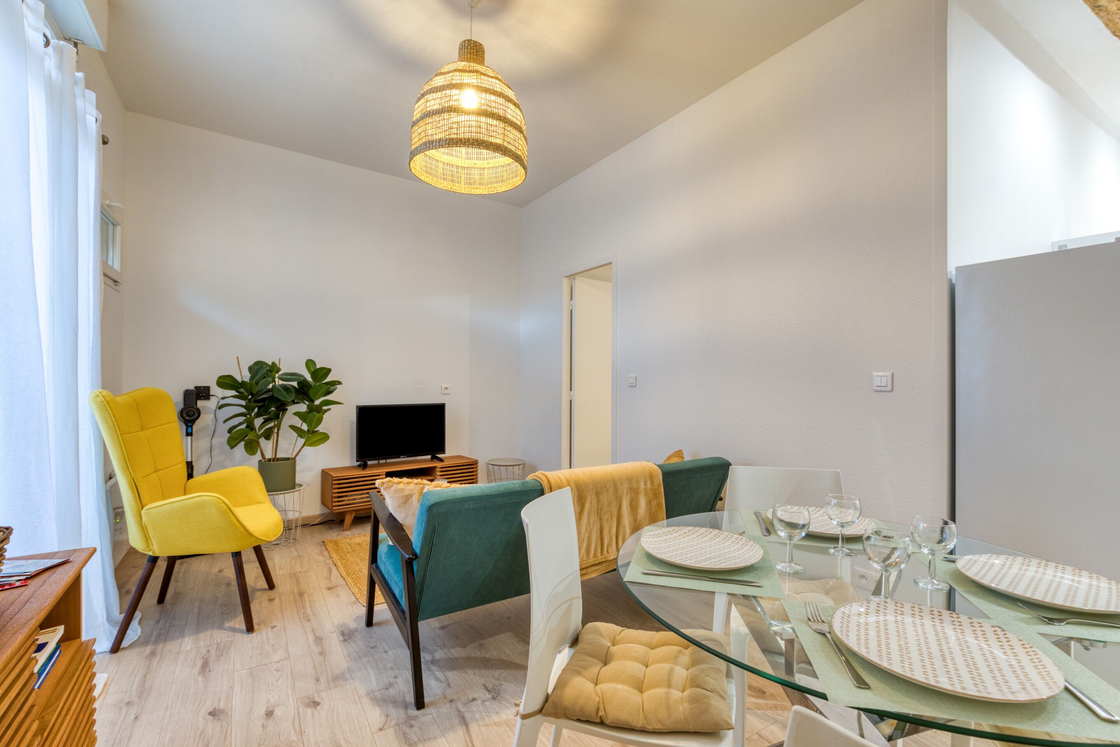 A modern living room with a dining area, a television, and a plant.