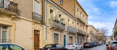 A street lined with historic buildings, parked cars, and a clear sky.