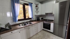 A kitchen with white cabinets, a stainless steel refrigerator, a microwave, and a stove.