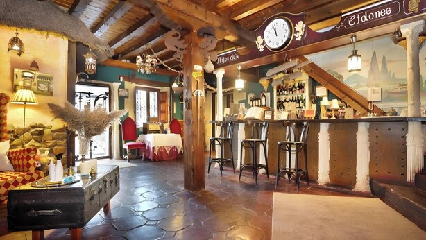 A rustic interior with a bar area, wooden beams, and a stone floor.