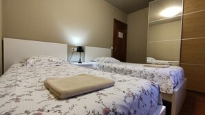 A hotel room with two beds, a nightstand, a lamp, a mirror, and a wooden wardrobe. - Country House 'Autxikoborda Bajo' with Mountain View, Private Garden and Wi-Fi (Elizondo)