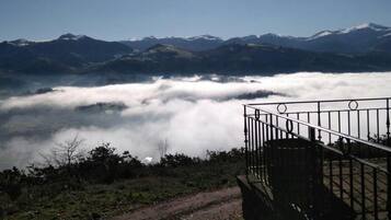 A mountain landscape with a clear sky, a railing, and a path leading towards the mountains.