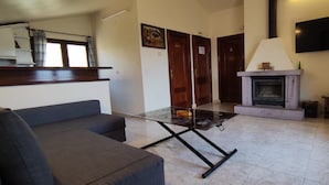 A living room with a sofa, a glass-top coffee table, a fireplace, and a television mounted on the wall.