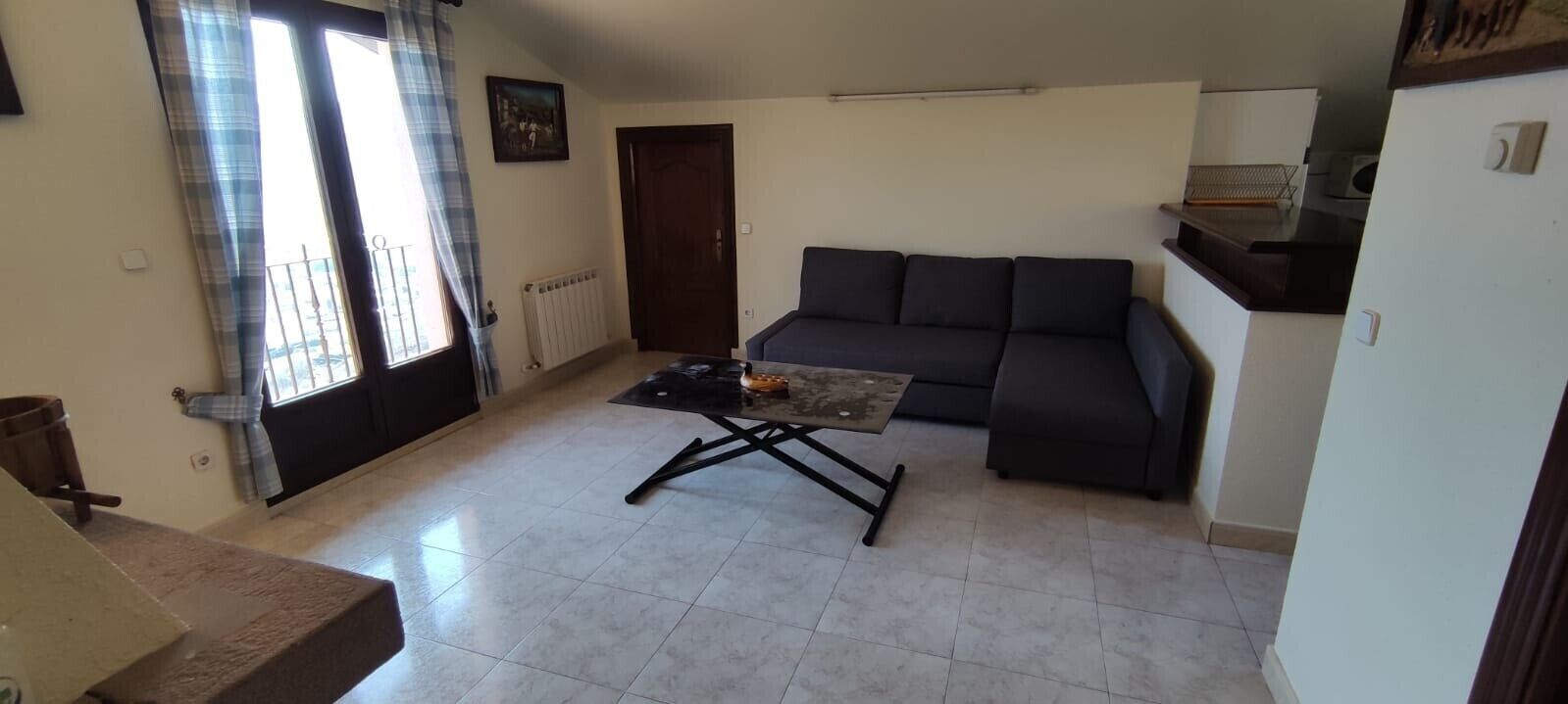 Un salon avec un canapé, une table basse, une porte et une fenêtre avec des rideaux.