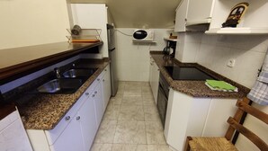A compact kitchen with a sink, stove, and microwave.