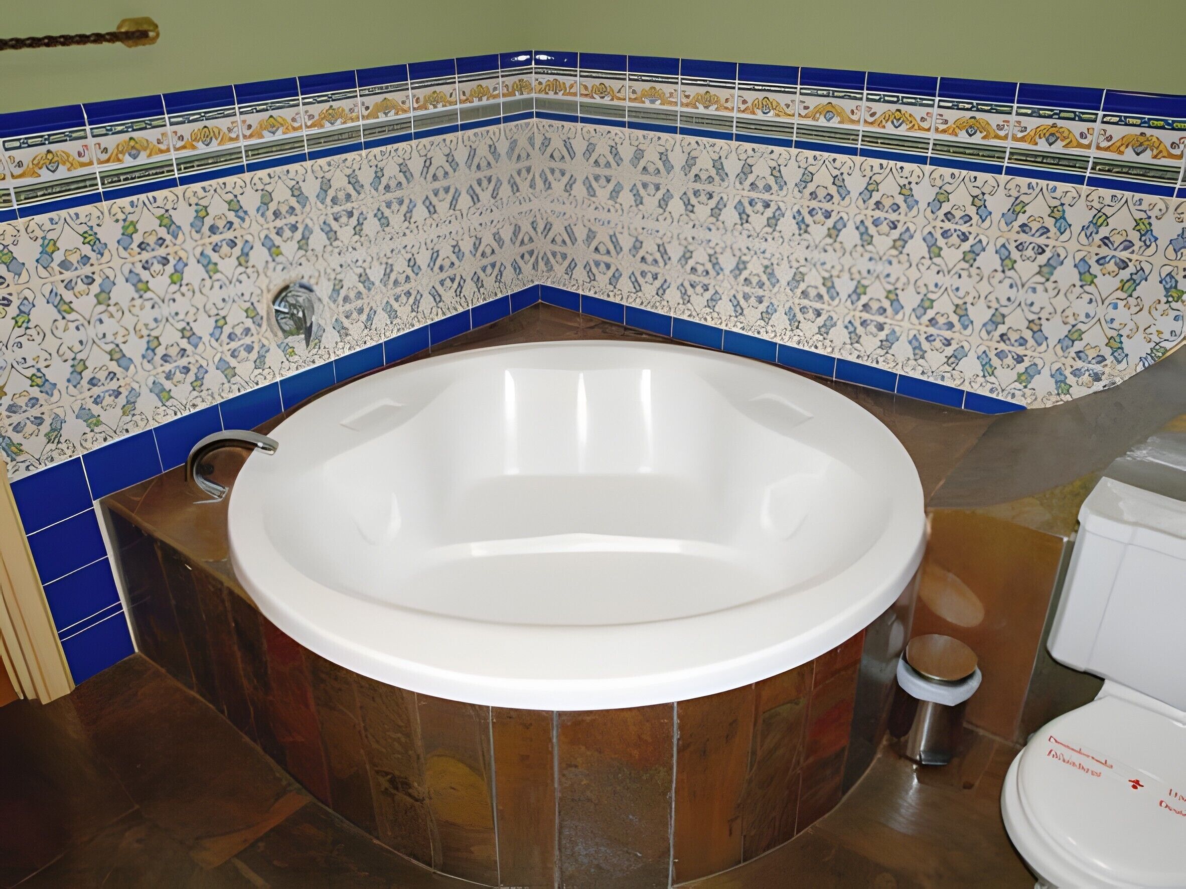 Un baño con una bañera independiente, un inodoro y un cubo de basura.