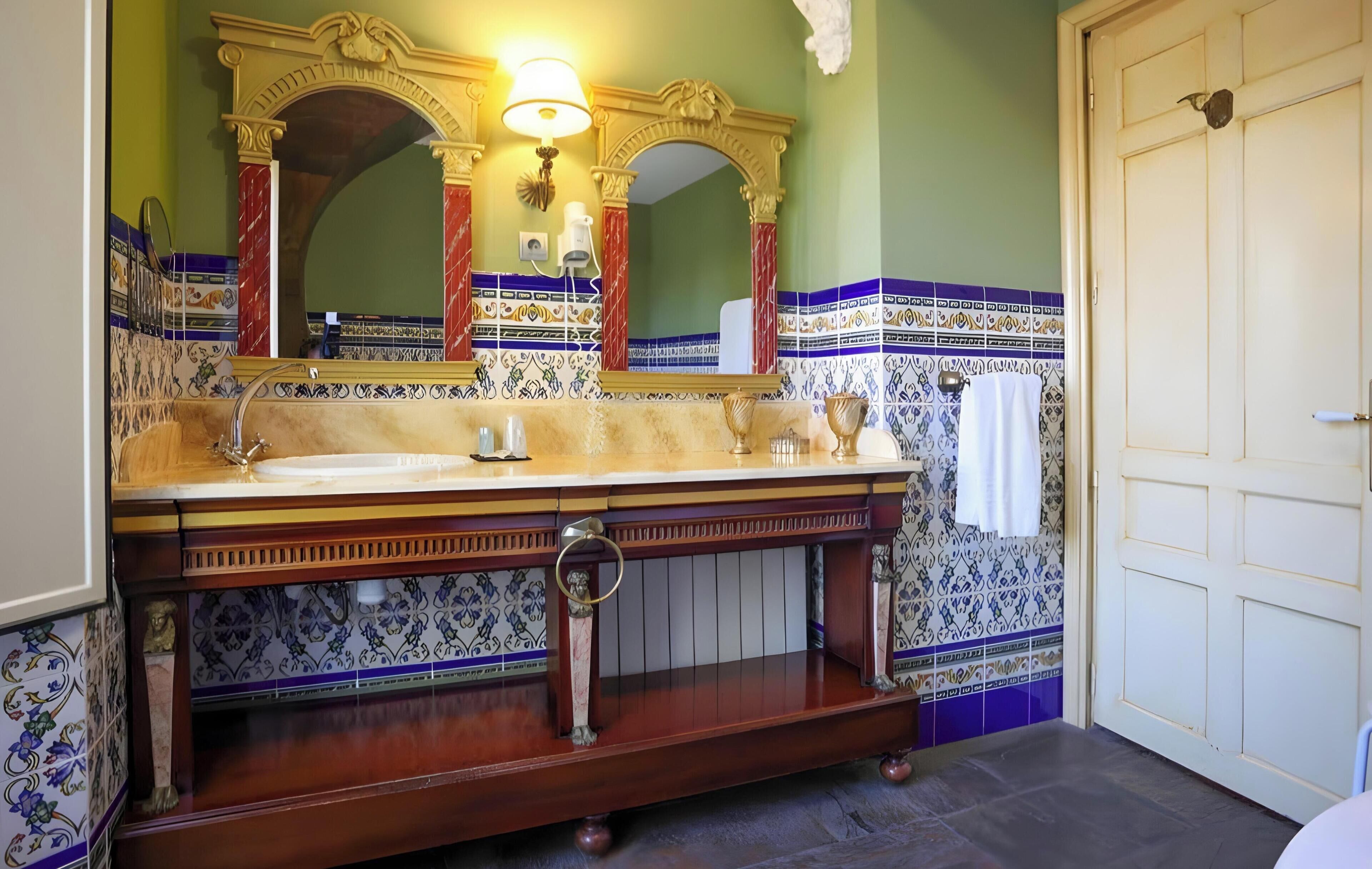 A bathroom with a wooden vanity, a large mirror, and patterned tiles.