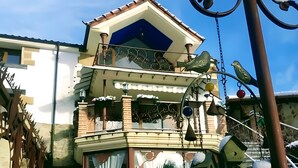A two-story building with a balcony, a decorative metal fence, and snow-covered plants. - Suite 5 with Mountain Views, Shared Terrace, and Wi-Fi (CIDONES)