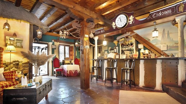 A rustic interior with a bar area, wooden ceiling, and hexagonal floor tiles.