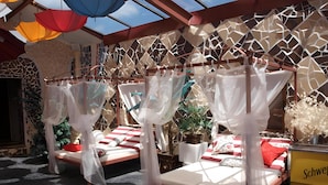 Two beds with white canopies, a patterned wall, and a plant in the corner.