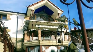 A two-story house with a balcony, a bird feeder, and snow-covered plants.