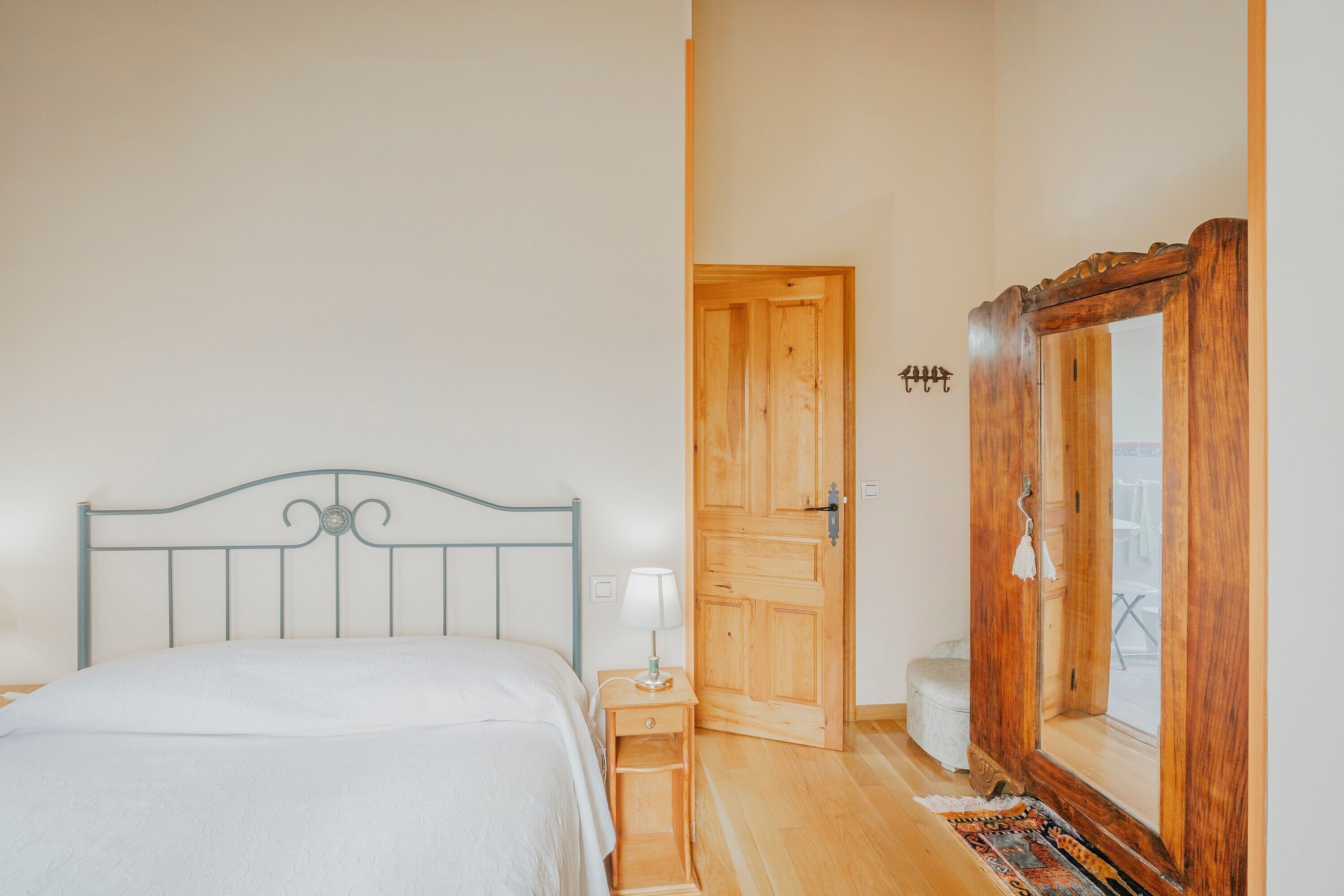Un dormitorio con cama, mesita de noche, armario de madera y espejo.