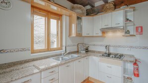 Une cuisine avec des meubles blancs, un plan de travail en granit, une fenêtre donnant sur un beau paysage et un extincteur.