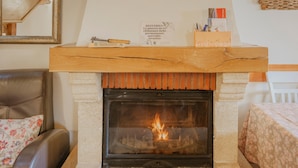 Une cheminée avec un feu, une étagère en bois et une inscription au-dessus.