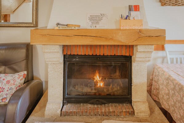 A fireplace with a fire, a wooden mantel, and a sign above it.