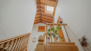Un escalier en bois avec un puits de lumière, une rampe en bois et une plante.