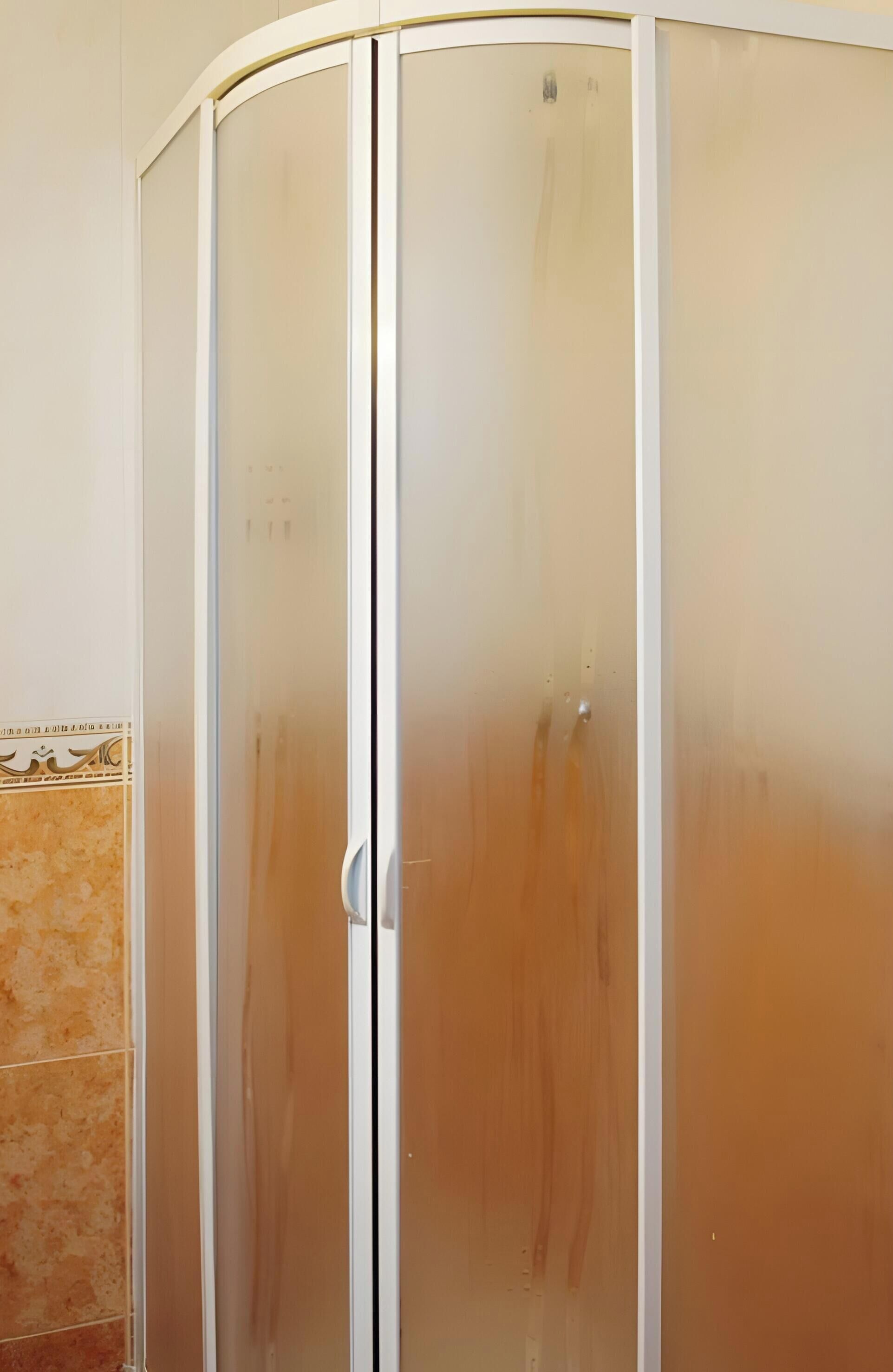Una habitació amb una porta corredissa, un mur revestit de rajoles i un terra de fusta.
