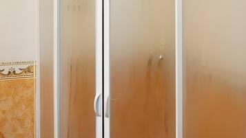 Una habitació amb una porta corredissa, un mur revestit de rajoles i un terra de fusta.