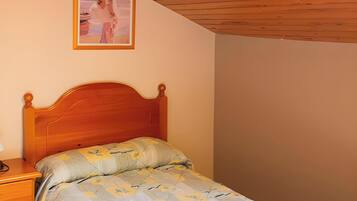 Un dormitorio con techo de madera, una cama con colcha floral, una mesita de noche y un cuadro enmarcado en la pared.