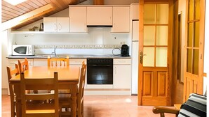 A kitchen with a dining table, chairs, a microwave, and a stove. - Apartment 'Yerga' with Wi-Fi (Tella)