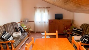 A cozy living room with a wooden ceiling, a sofa set, a dining table, and a television on a wooden cabinet. - Apartment 'Yerga' with Wi-Fi (Tella)