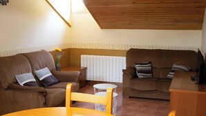 A cozy living room with two brown sofas, a wooden coffee table, and a white radiator. - Apartment 'Santa Justa' with Mountain View, Wi-Fi and Air Conditioning (Hospital)