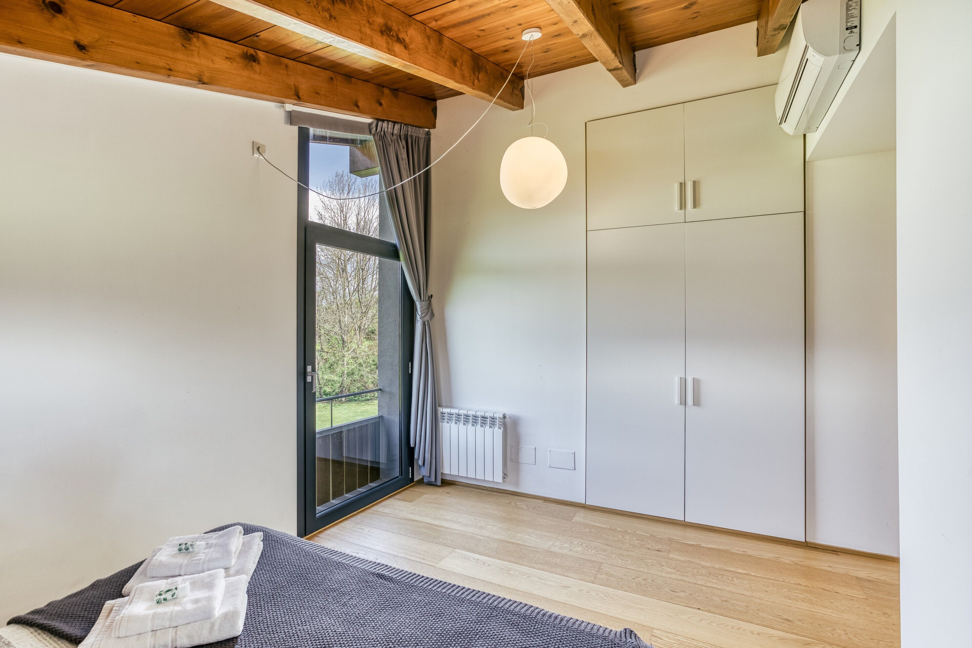 A bedroom with a bed, a wardrobe, a radiator, and a window with curtains.