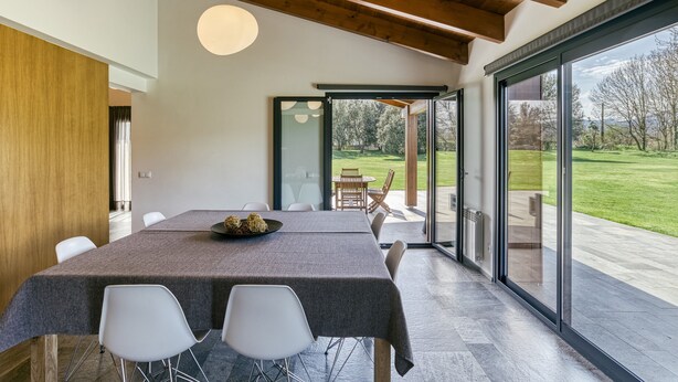 A modern dining area with a table, chairs, and a view of the outdoors.