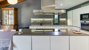 A modern kitchen with a central island, stainless steel appliances, and a wooden cabinet.