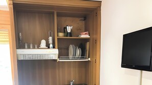 A compact kitchen with a sink, stove, and a dining table with a remote control.