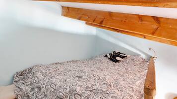 Un dormitorio con techo de madera, colcha estampada y un objeto colgante.