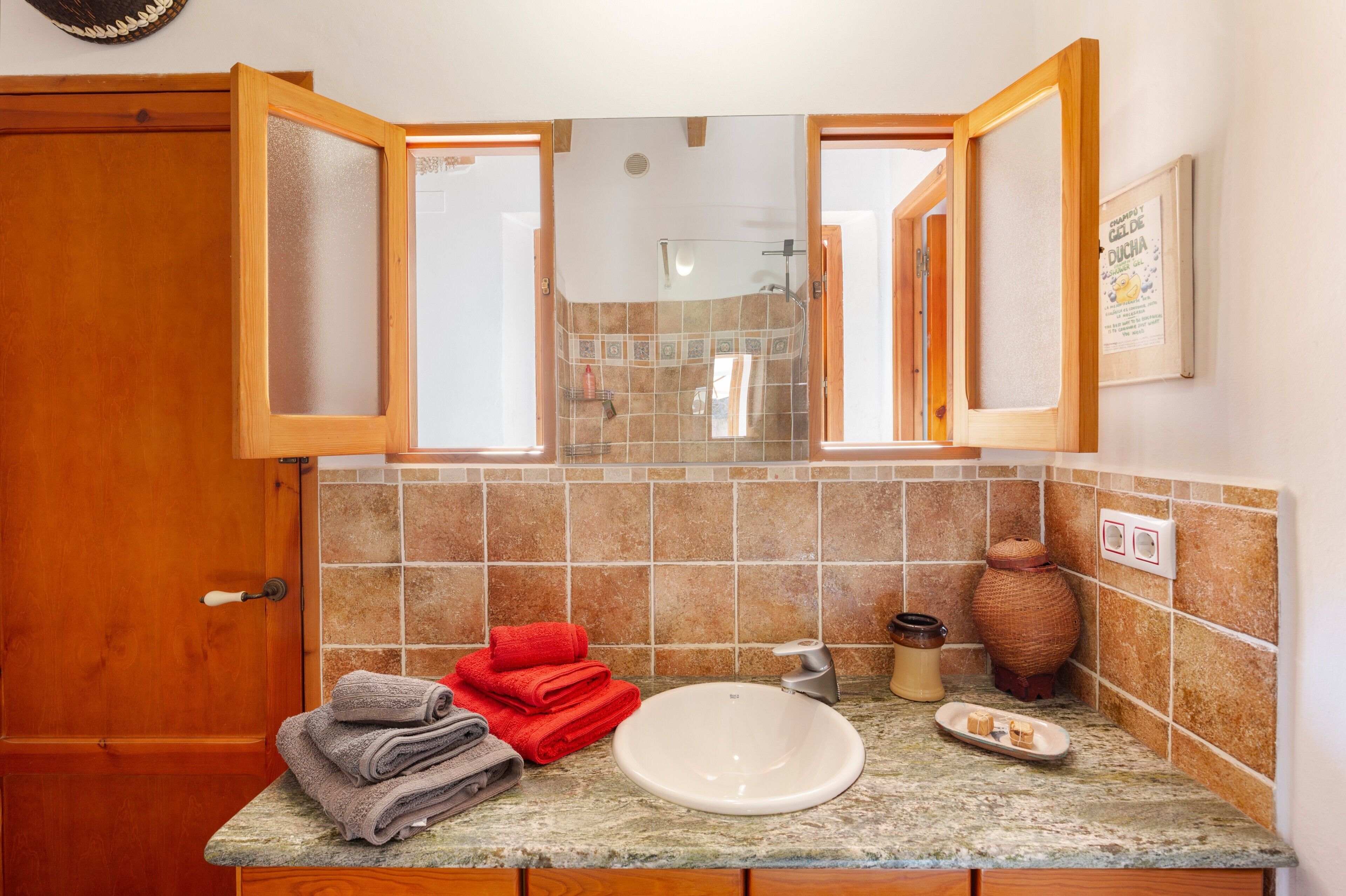 Baño con lavabo, espejo, toallero y zona de ducha.