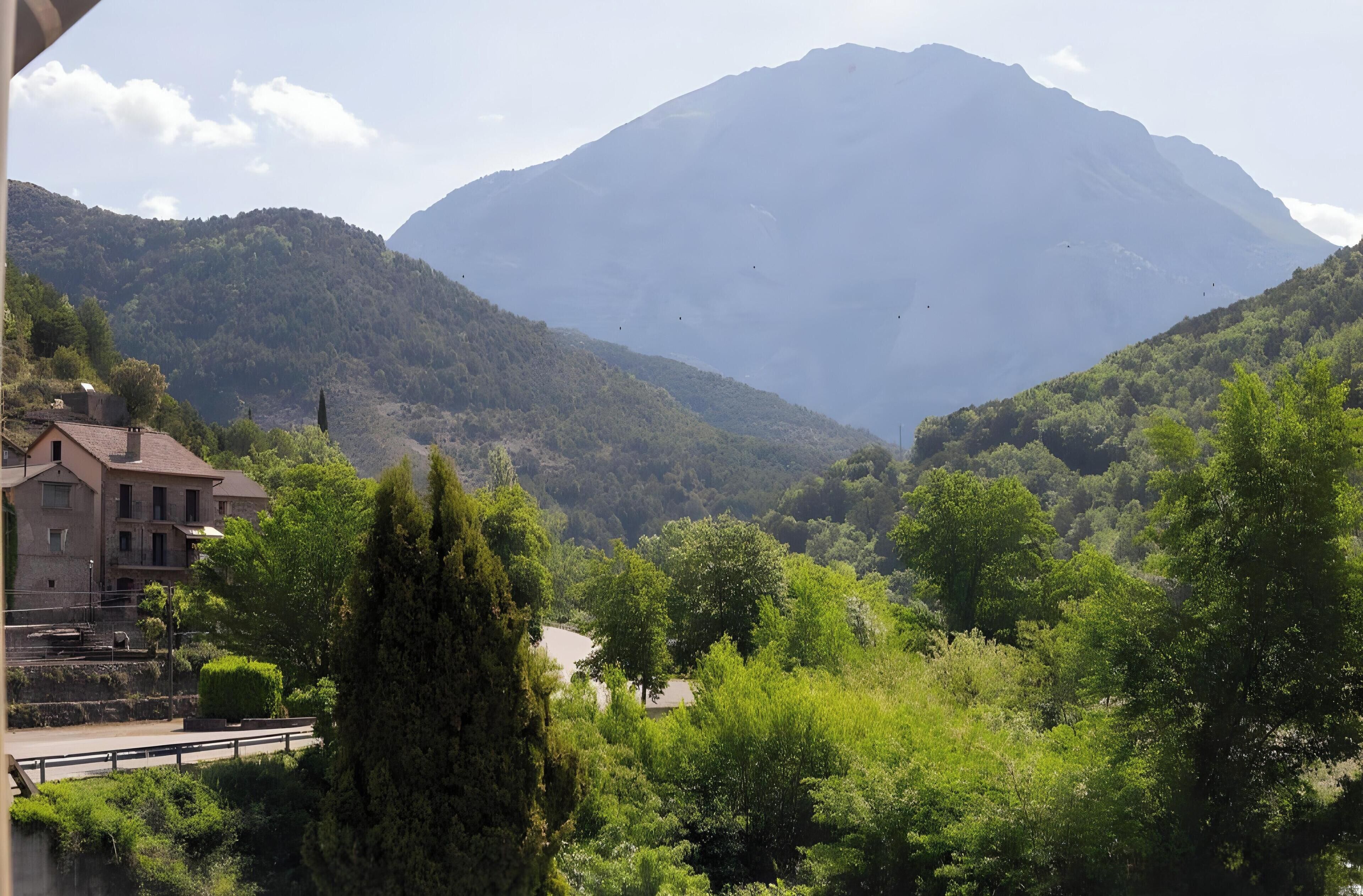 Un paisaje montañoso con un edificio en primer plano.