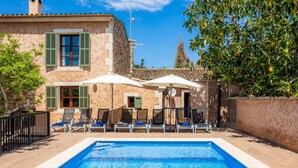 A poolside area with a rectangular pool, lounge chairs, and umbrellas.
