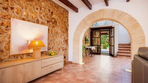A stone wall, a wooden console table with a lamp, and an archway leading to a staircase.