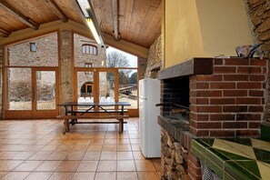 Un intérieur rustique avec un mur en pierre, un plafond en bois et une cheminée en briques.