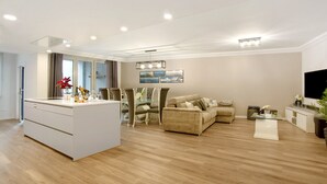 Una sala de estar moderna con un sofá, una mesa de comedor y una zona de cocina con una isla blanca.