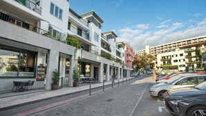 Una calle adoquinada flanqueada por edificios de varios pisos, algunos con balcones y terrazas.