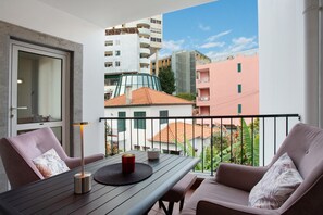 Een balkon met een tafel, stoelen en een lamp.