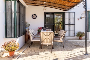 An outdoor patio with a table and chairs, a potted plant, and a decorative plate on the wall. - Holiday Home 'Palmera' with Mountain View, Private Pool and Wi-Fi (Málaga)